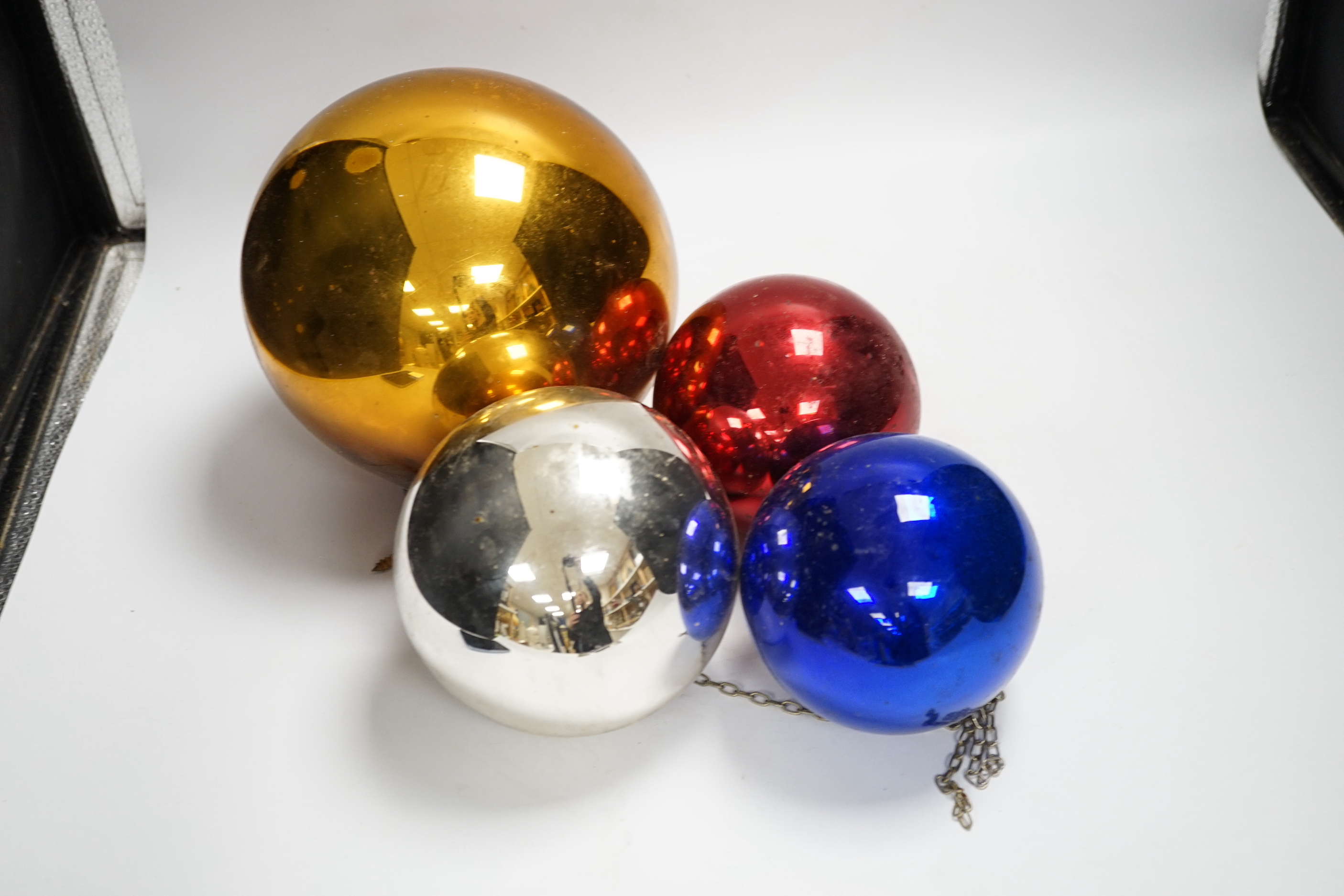 A gold witch’s ball and three small witch’s balls (silver, red and blue)